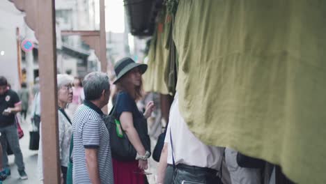 Japanese-People-Going-Through-A-Noren-Door-Curtain-In-Kyoto,-Japan