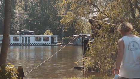 Pareja-Joven-Caminando-Hacia-La-Orilla-Del-Río-Sosteniendo-Una-Tabla-De-Remo