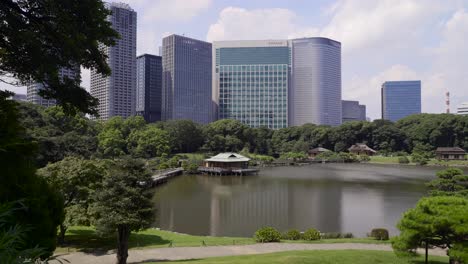 Amplia-Vista-Sobre-La-Casa-De-Té-Japonesa-En-Los-Jardines-Hamarikyu-En-Tokio-Con-Un-Telón-De-Fondo-De-Modernos-Rascacielos