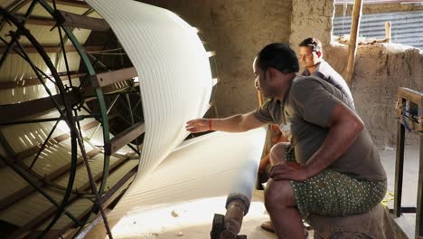 Rural-Indian-workers-weaving-cotton-in-spinning-machine-inside-clay-house