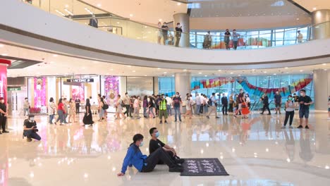 Zwei-Demonstranten-Setzen-Sich-Während-Einer-Regierungsfeindlichen-Demonstration-Im-IFC-Einkaufszentrum-Im-Zentralen-Bezirk-Von-Hongkong-Mit-Einem-Transparent-Auf-Den-Boden,-Auf-Dem-Sie-Die-Unabhängigkeit-Hongkongs-Fordern