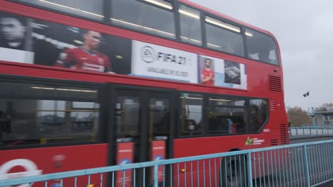 Autobús-Rojo-De-Londres-Conduciendo-Sobre-El-Puente-De-La-Torre-Con-El-Icónico-Horizonte-De-Rascacielos-En-Segundo-Plano