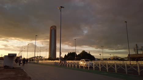 Coches-Conducidos-Por-Personas-Y-Torre-Pelli-En-El-Paisaje-Dorado-Del-Atardecer,-Sevilla,-España