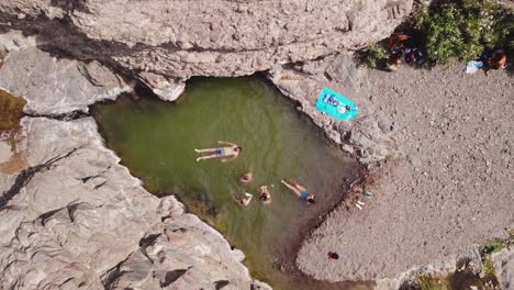 Grupo-De-Amigos-Disfrutan-De-Un-Día-De-Natación-En-Una-Piscina-Natural-De-Agua-Dulce-En-Medio-De-Un-Valle-Seco-Y-árido-De-Wadi