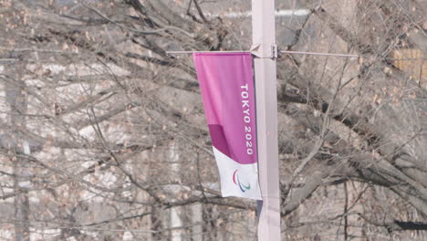 A-fixed-shot-of-a-Banner-of-the-cancelled-Tokyo-2020-Olympic-waving-with-a-tree-in-the-background-in-Tokyo,-Japan