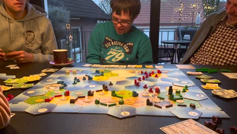 Happy-family-and-man-with-down-syndrome-playing-board-game-indoors-during-Christmas-time,close-up-shot