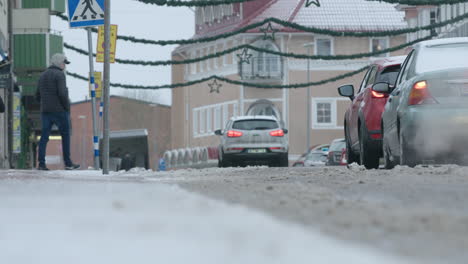 An-elderly-woman-with-walking-poles-and-teens-cross-a-snowy-road-in-Sweden,-during-the-covid-19-pandemic