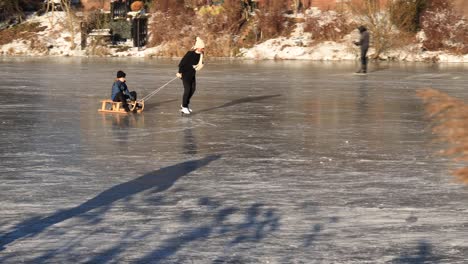 Gente-Patinando-Sobre-Hielo-En-El-Canal-Con-Caña-En-Primer-Plano-Panoramización-Para-Revelar-Más-Actividades-Recreativas-En-La-Orilla