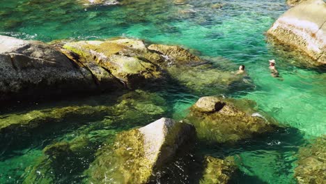 Menschen-Schwimmen-Im-Klaren-Tropischen-Meer-Zwischen-Felsen-Eines-Versteckten,-Einsamen-Strandes