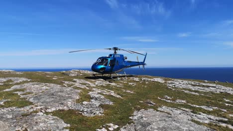 Privathubschrauber-Thront-Auf-Dem-Gipfel-Einer-Bergklippe-Mit-Blick-Auf-Die-Blaue-Meereslandschaft-Und-Startet-Den-Propeller