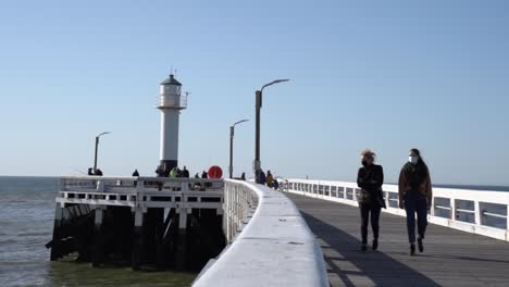 Personas-Enmascaradas-Caminando-En-La-Empalizada-De-Nieuwpoort,-Bélgica-Durante-La-Pandemia-De-Coronavirus