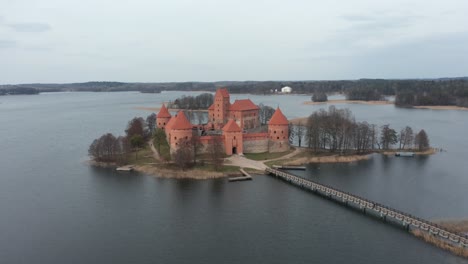 Antena:-Castillo-De-La-Isla-Trakai-Rodeado-Por-Un-Lago-En-Un-Día-Sombrío-Con-Un-Puente-De-Madera-Que-Conecta-La-Siguiente-Isla