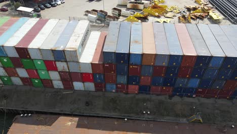 Piles-Of-Containers-At-Industrial-Port-Of-Dordrecht-In-Rotterdam,-Netherlands-With-Heavy-Construction-Materials-And-Cars-Parked-In-Background