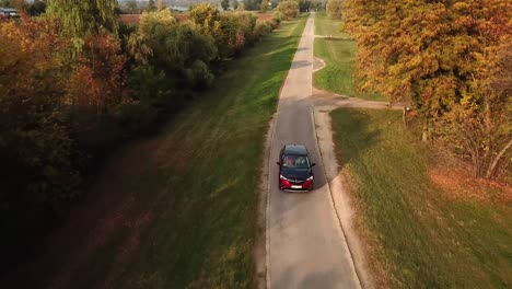 Vista-Aérea-De-Un-Coche-Opel-Grandland-Negro-Y-Rojo-Acelerando-En-Una-Carretera-De-Campo,-Al-Atardecer