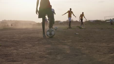 Varios-Hombres-Negros-Juegan-Al-Fútbol-En-Un-Campo-De-Tierra