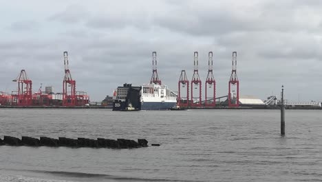 Cargo-container-ship-tanker-vessel-guidance-by-tug-boats-towards-Peel-port-harbour-cranes