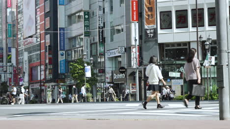 Pedestrians-and-cyclists-wait-before-crossing-a-busy-street-in-Tokyo-with-umbrellas-to-shield-from-the-hot-summer-sun