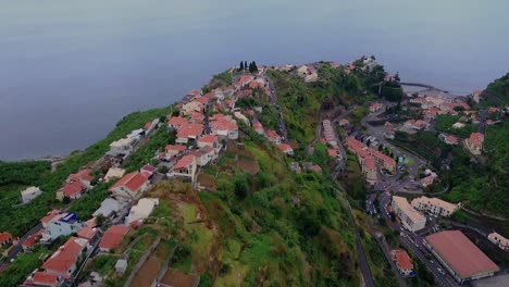 Edificios-De-Hotel-En-La-Cima-De-Un-Exuberante-Acantilado-Verde-Con-Una-Visión-General-Del-Brumoso-Océano-Atlántico-En-Ponta-Do-Sol,-Archipiélago-De-Madeira-En-Portugal