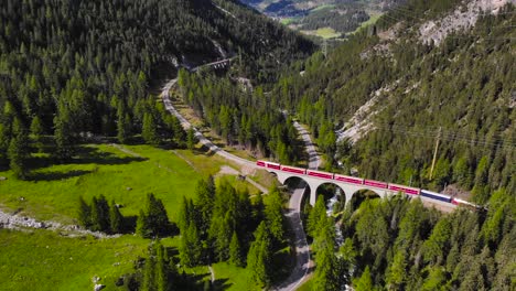 Aerial:-red-train-in-mountainous-landscape