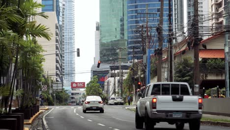 Long-avenue-with-tropical-plants-and-tall-buildings-where-several-vehicles-stop-for-a-red-light-in-Panama-City