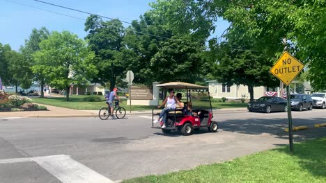 Golf-Cart-driving-around-on-an-island-with-Perry's-Victory-International-Peace-Memorial-signboard-in-the-background,-Put-in-Bay-South-Bass-island-Ohio-USA