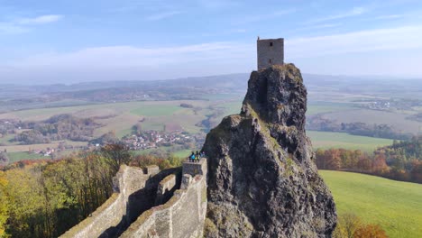 Vista-De-Una-Torre-De-Las-Ruinas-Del-Castillo-Checo-Trosky-En-Una-Roca-Alta-Con-Visitantes,-Soleado