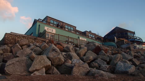 Blick-Nach-Oben-Auf-Newquays-Fistral-Beach-Bar-Und-Restaurant-Mit-Blauem-Himmel-Am-Abend,-Cornwall,-England,-Vereinigtes-Königreich,-Weitwinkelschwenk