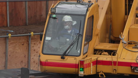 Skilled-Worker-In-Safety-Hard-Hat-Operating-Mobile-Crane-Moving-In-Slow-Motion-Under-The-Rain