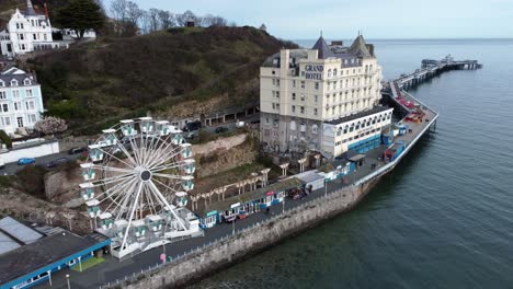 Llandudno-pier-Victorian-promenade-Ferris-wheel-attraction-and-Grand-hotel-resort-aerial-view-pull-away