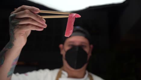 Chef-Latino-Sosteniendo-Atún-Fresco-Rosado-Para-Preparar-Sushi-Con-Mascarilla-En-Cámara-Lenta