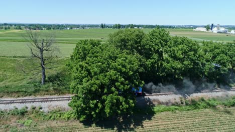 Eine-Luftaufnahme-Von-Thomas,-Der-Tenderlok,-Die-Rauch-Ausbläst-Und-An-Einem-Schönen-Tag-Von-Alleine-über-Das-Ackerland-Und-Die-Landschaft-Fährt