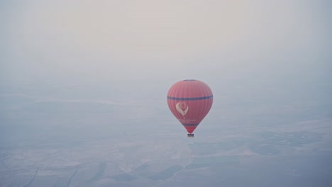 Globo-De-Aire-Caliente-Rojo-Volando-Sobre-El-Paisaje-De-Marruecos,-Vista-Aérea-De-Mano