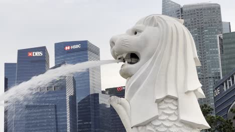 Primer-Plano-De-La-Icónica-Mascota-De-Singapur,-Criatura-Mítica-Merlion-En-El-área-Metropolitana-Del-Centro-Con-Edificios-Comerciales-Y-Financieros-En-El-Fondo