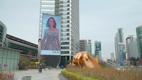 Statue-Of-Gangnam-Style-Sculpture-And-COEX-Media-Tower-Electronic-Display-In-Gangnam-gu,-Seoul,-South-Korea