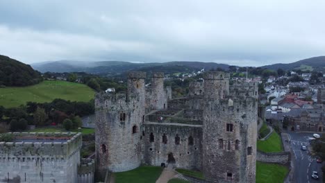 Conwy-Castillo-Medieval-Ciudad-Amurallada-Mercado-Vista-Aérea-Elevándose-Sobre-Los-Turistas-Caminando-Almena-Fortificación