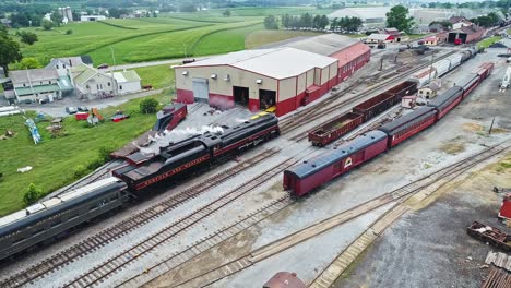 An-Aerial-View-of-an-Antique-Steam-Passenger-Train-Approaching-Station-Thru-Freight-Yard