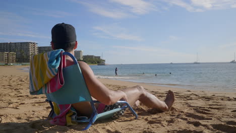 A-video-has-been-shot-from-the-backside-of-a-handsome-young-man-sunbathing-on-a-chair-and-a-towel-is-seen-on-the-chair