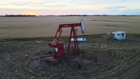 Toma-De-Drones-De-Gran-Angular-De-Una-Bomba-Roja-Activa-En-El-Campo-De-América-Del-Norte-Al-Atardecer