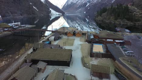 Flying-over-Njardarheimr-viking-village-in-Gudvangen-towards-Naroyfjorden---Calm-winter-morning-aerial-Norway