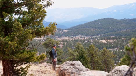 Un-Excursionista-Masculino-Solitario-Camina-Hacia-Un-Mirador-Y-Se-Detiene-Para-Admirar-La-Vista-Mientras-El-Viento-Mueve-Los-árboles-A-Su-Alrededor