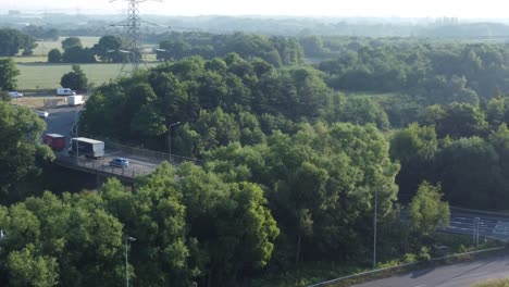 Luftaufnahme-über-Die-Britische-Waldlandschaft-Mit-Fahrzeugen,-Die-Auf-Der-Autobahn-Im-Hintergrund-Fahren