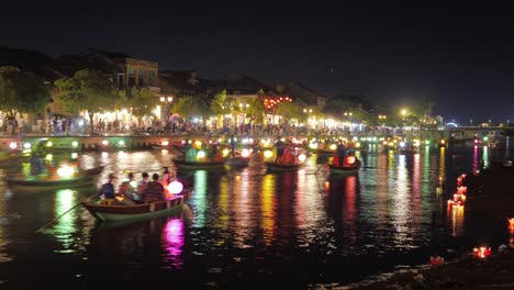 Zeitraffer-Laternenfest-Von-Hoi-An,-Farbenfrohe,-Mit-Laternen-Beleuchtete-Nächte,-Viel-Verkehr-Mit-Booten-Und-Kanus-Auf-Dem-Kanal-Und-Dem-Fluss,-Schwimmendes-Segeln-Entlang-Des-Kais,-Touristenmassen,-Leuchtende-Laternen-Auf-Dem-Wasser