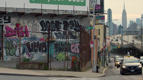 Heavily-Graffitied-Building-In-Queens,-New-York,-With-Empire-State-Building-In-Background