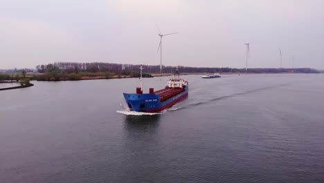 Vista-Aérea-Del-Carguero-Wilson-Mosel-Acercándose-A-Lo-Largo-De-Oude-Maas-Con-Turbinas-Eólicas-Todavía-En-El-Fondo-En-Barendrecht