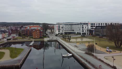 Antena-Acercándose-Al-Scandic-Hotel-Kristiansand---Avanzando-Cerca-De-La-Superficie-Del-Agua-Mientras-Asciende-Y-Pasa-El-Patio-De-Recreo-Hacia-El-Edificio-Del-Hotel