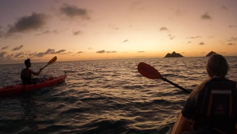 Pareja-Remando-Kayaks-En-El-Mar-Hacia-El-Horizonte-Del-Atardecer,-Cámara-Lenta