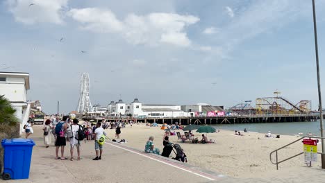 People-walk-along-the-sea-front-towards-the-pier-in-Clacton-on-Sea,-Essex,-UK