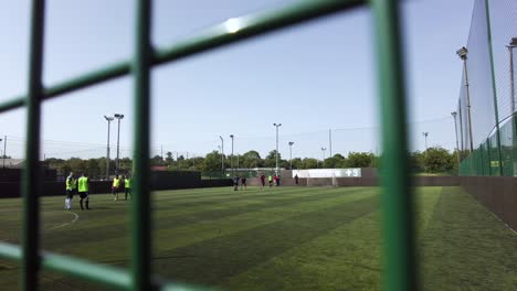 Una-Toma-Abstracta-De-Dos-Equipos-De-Fútbol-Que-Se-Preparan-Para-Comenzar-Antes-De-Un-Partido-Social-De-Fútbol-Amateur-De-5-Jugadores-En-Un-Campo-De-Césped-Artificial-En-Goals-Ruislip,-Inglaterra