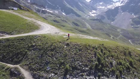 Ciclista-De-Montaña-Volando-Su-Dron-En-Las-Montañas-Verbier-Por-Encima-De-Los-Senderos