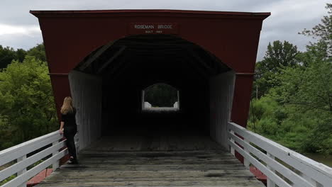 Eine-Touristin-Blickt-Auf-Die-Roseman-Bridge-Im-Madison-County,-Während-Die-Kamera-Auf-Die-Umliegenden-Bäume-Schwenkt